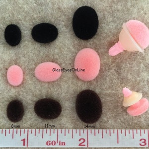 May include: Assortment of black, brown, and pink felt pom-poms in various sizes, measured in inches on a ruler.  The pom-poms are displayed on a beige surface.  The text "GlassEyesOnline" is visible in the image.