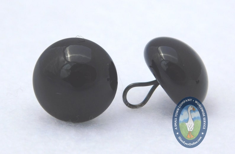 May include: Two black plastic safety eyes with a black plastic loop on one eye. The eyes are approximately 1 inch in diameter.