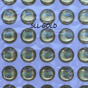 May include: A sheet of 36 iridescent gold round plastic eyes, each with a black pupil. The sheet is labeled "SLL-GOLD".