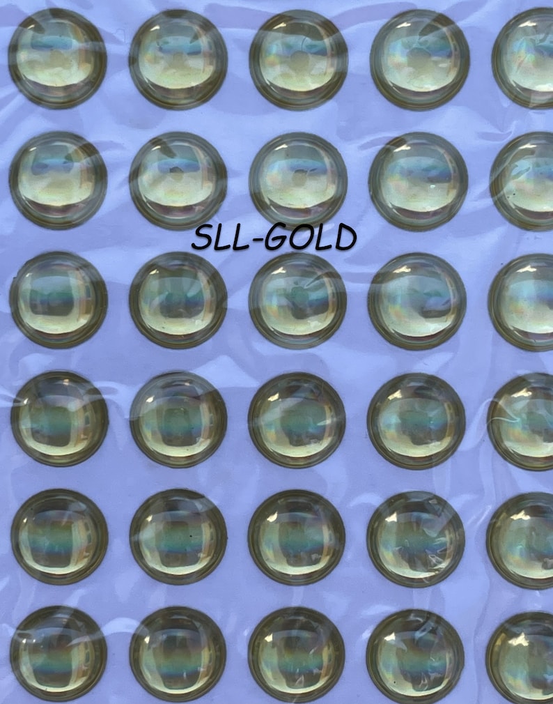 May include: A sheet of 36 iridescent gold round plastic eyes, each with a black pupil. The sheet is labeled "SLL-GOLD".