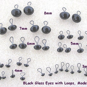 May include: Assortment of black glass eyes with loops in various sizes, ranging from 3mm to 8mm. The eyes are arranged in rows by size, with the largest eyes at the top and the smallest eyes at the bottom. The text "Black Glass Eyes with Loops, Model LP201" is printed at the bottom of the image.