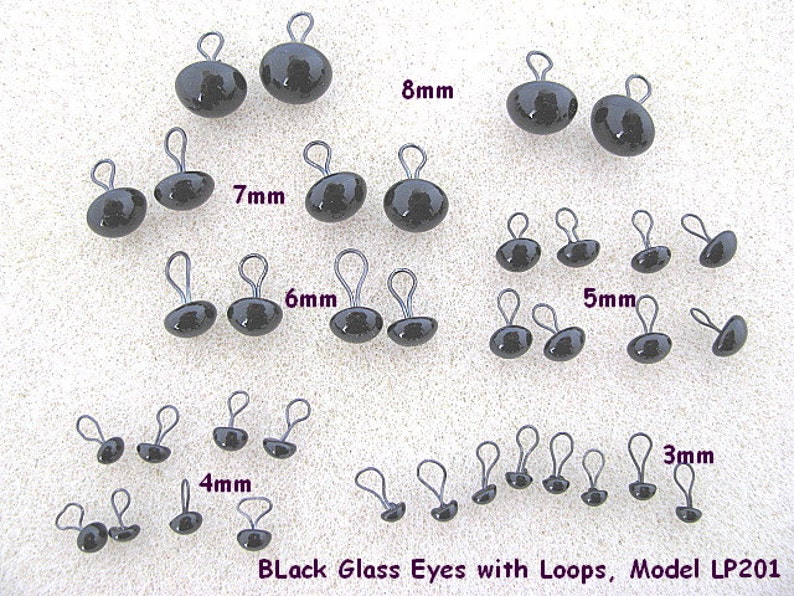 May include: Assortment of black glass eyes with loops in various sizes, ranging from 3mm to 8mm. The eyes are arranged in rows by size, with the largest eyes at the top and the smallest eyes at the bottom. The text "Black Glass Eyes with Loops, Model LP201" is printed at the bottom of the image.