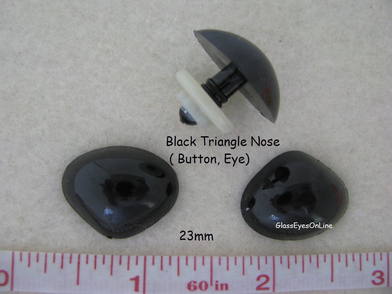 Pode incluir: Tr&ecirc;s bot&otilde;es de nariz de pl&aacute;stico preto em forma de tri&acirc;ngulo, um com um poste de pl&aacute;stico branco, medindo 23 mm de di&acirc;metro. Nariz triangular preta (bot&atilde;o, olho) GlassEyesOnLine
