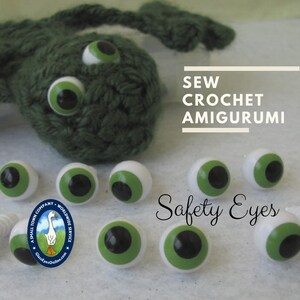 May include: Green crocheted amigurumi toy with large black and green safety eyes.  A close-up of several additional safety eyes in various sizes with black pupils and green irises.  The text "Sew Crochet Amigurumi Safety Eyes" is visible in the image.
