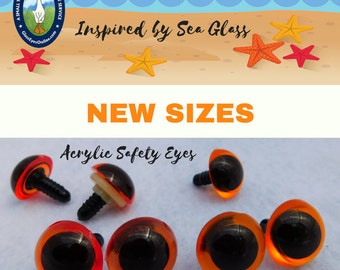 May include: Acrylic safety eyes in various sizes, with a black pupil and orange-tinted iris. The image includes the text "NEW SIZES" and "Acrylic Safety Eyes". The background features a beach scene with starfish and the text "Inspired by Sea Glass".