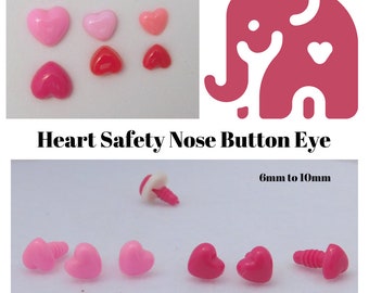 Op de afbeelding: Assortiment van roze en rode hartvormige veiligheidso ogen voor knutselen. De ogen zijn 6 mm tot 10 mm groot. De afbeelding toont ook een roze olifant met een hart op zijn borst. De tekst "Heart Safety Nose Button Eye" en "GlassEyesOnline.com" is zichtbaar.