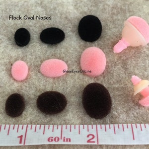 May include: Flock oval noses in black, brown, and pink. The noses are various sizes and are shown next to a ruler with inch markings.  Flock Oval Noses.