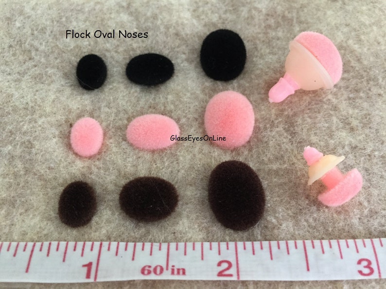 May include: Flock oval noses in black, brown, and pink. The noses are various sizes and are shown next to a ruler with inch markings.  Flock Oval Noses.