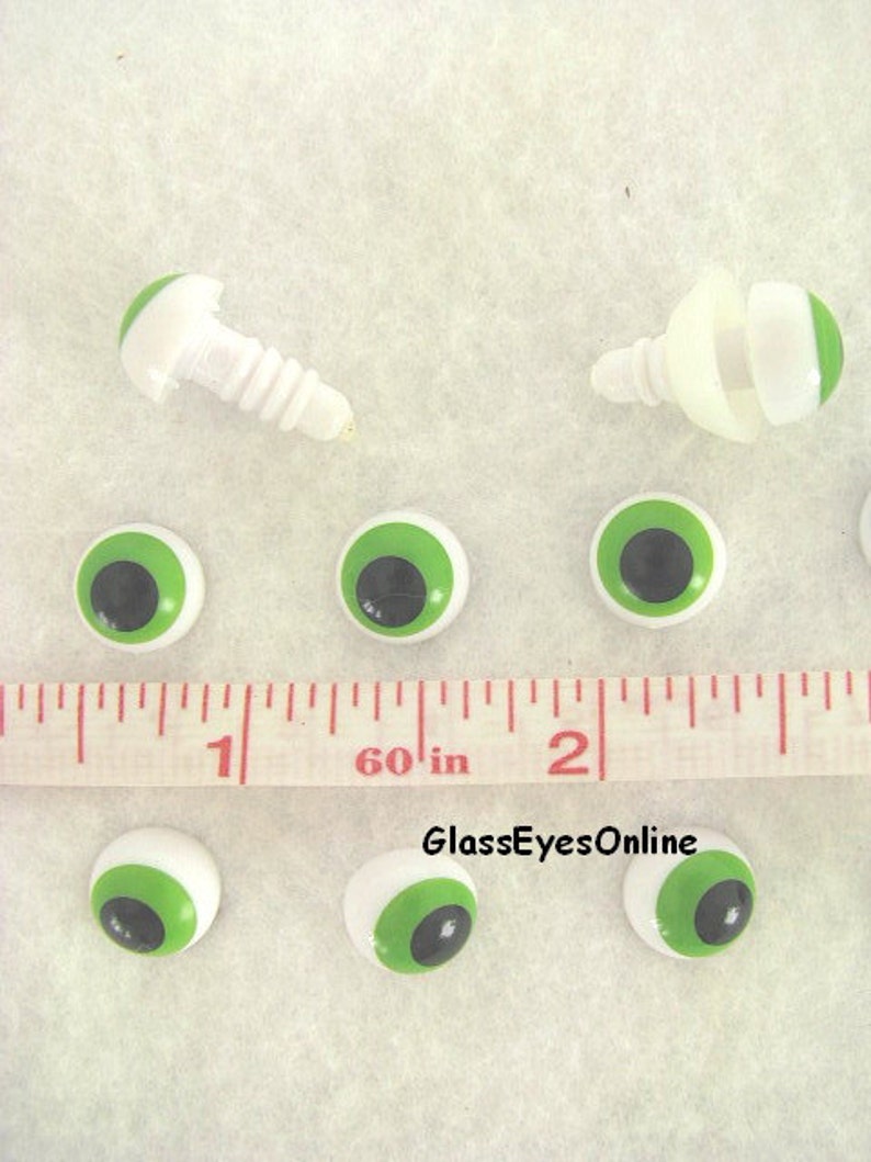 May include: Green and black plastic safety eyes with white backs, measuring 1 inch in diameter. The eyes are shown next to a ruler and two sets of eye fasteners.
