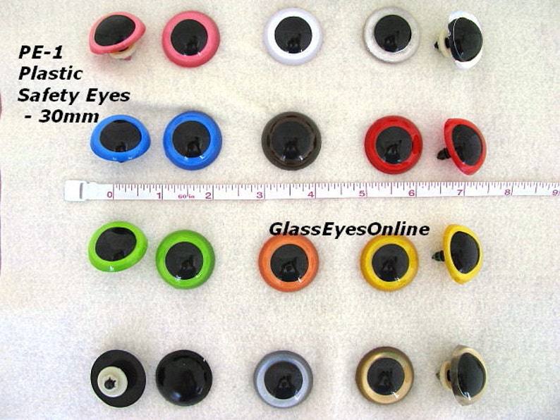 May include: Assortment of 30mm plastic safety eyes in various colours, including black, white, red, blue, green, orange, yellow, brown, and silver. The eyes have a black pupil and a white or coloured ring around the pupil. The eyes are attached to a plastic post with a washer.