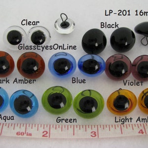 May include: A collection of 16mm glass eyes in various colors, including clear, black, dark amber, blue, violet, aqua, green, and light amber. The text "GlassEyesOnLine" and "LP-201 16mm" are visible.