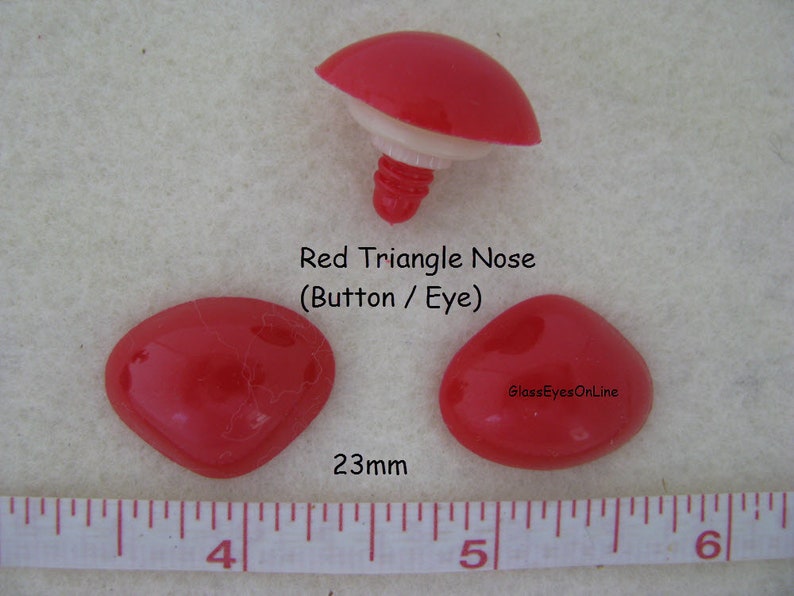 Pode incluir: Nariz de pl&aacute;stico vermelha em forma de tri&acirc;ngulo para artesanato, medindo 23 mm de largura. O nariz &eacute; mostrado ao lado de uma r&eacute;gua para refer&ecirc;ncia de tamanho. GlassEyesOnline.