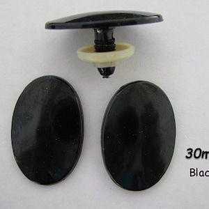 May include: Three black plastic oval-shaped buttons, each measuring 30mm in diameter. The buttons have a smooth, glossy finish. The text "30mm Black" is visible in the lower right corner of the image.