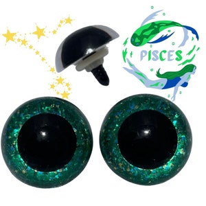 May include: Two green glitter safety eyes with black pupils and a silver plastic safety eye with a black screw. The image also includes a green and blue illustration of a mermaid with the word "Pisces" written below.