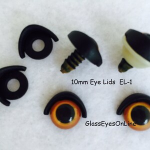 May include: A set of 10mm black plastic eye lids for stuffed animals. The lids are designed to be sewn onto the animal's head and have a small screw to secure them in place. The text "10mm Eye Lids EL-1" and "GlassEyesOnLine" are visible in the image.