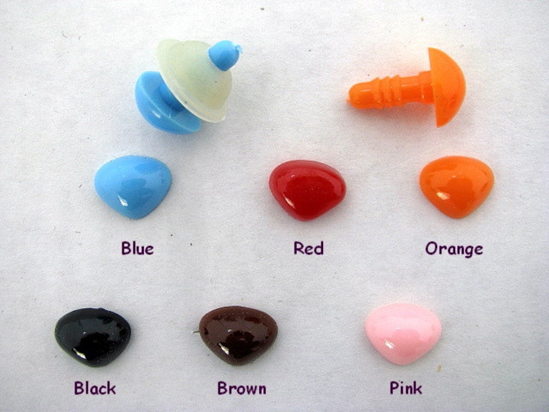May include: Assortment of colorful plastic safety eyes for crafts. The eyes are in various colors, including blue, red, orange, black, brown, and pink. The eyes are in a heart shape and have a flat back.