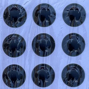 May include: A sheet of black and gray round stickers with a clover design. The stickers are arranged in rows on a white background.