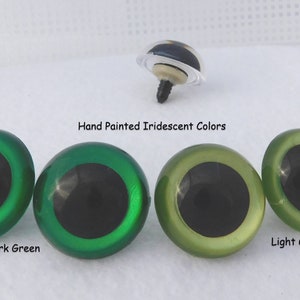 May include: Four plastic safety eyes for crafts, with black pupils and iridescent green and light green colors. The eyes are labeled "Dark Green" and "Light Green".