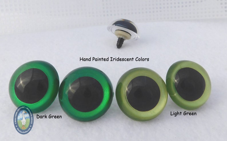 May include: Four plastic safety eyes for crafts, with black pupils and iridescent green and light green colors. The eyes are labeled "Dark Green" and "Light Green".