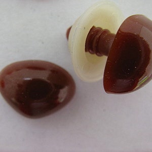 May include: Two brown plastic safety eyes for crafts. One eye is attached to a white plastic washer. The eyes are glossy and have a slight sheen.