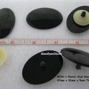 May include: Black plastic oval nose for crafts, measuring 1.85 inches long, 1.26 inches wide, and 0.2 inches thick. The image shows several noses, some with a white plastic backing. Text on the image reads "#ON-1 Plastic Oval Nose - 47mm x 32mm x 5mm Thick."