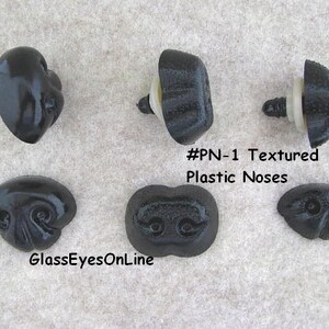 May include: Five black plastic noses for doll making or craft projects. The noses have a textured surface and come in different shapes and sizes. #PN-1 Textured Plastic Noses