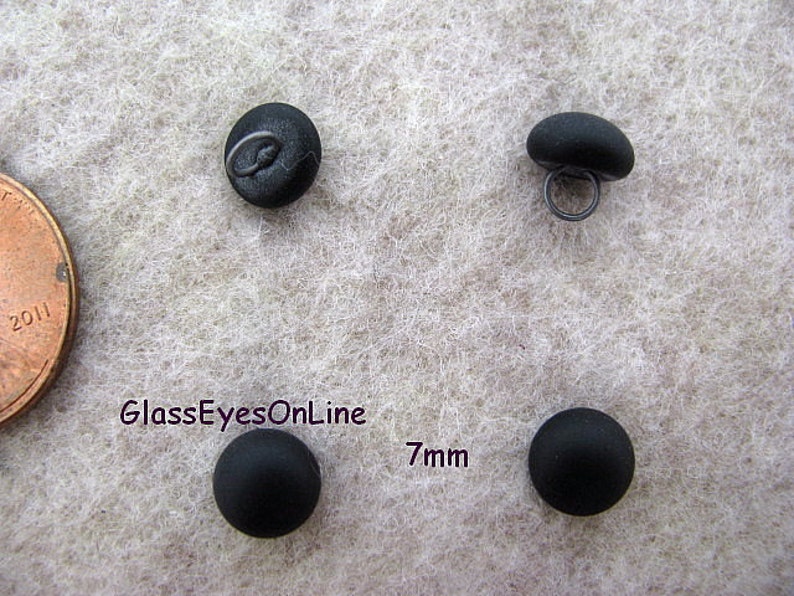 May include: Four black glass buttons with a 7mm diameter. The buttons have a shank on the back for sewing.
