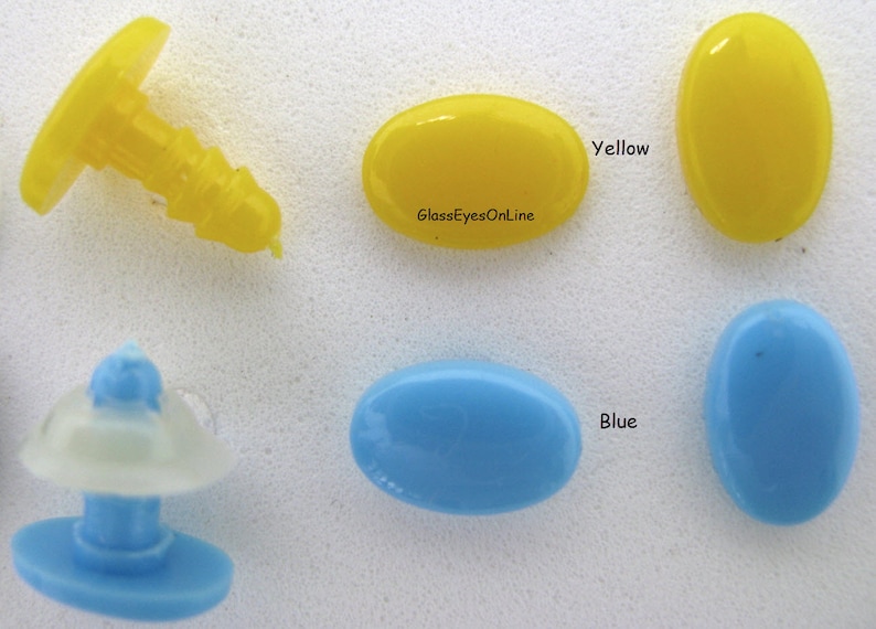 May include: Two oval-shaped glass eyes, one yellow and one blue, with a small plastic eye socket in the background. The text "GlassEyesOnline" is visible on the yellow eye.