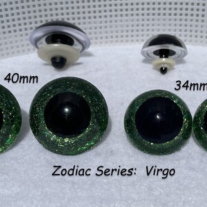 May include: Two pairs of green glitter safety eyes for stuffed animals. The larger pair is 40mm and the smaller pair is 34mm. The eyes have black pupils and a green glitter finish. The text "Zodiac Series: Virgo" is printed below the eyes.