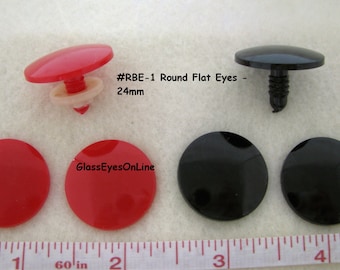 Op de afbeelding: Twee paar ronde, platte plastic ogen, een paar rood en een paar zwart. De ogen hebben een diameter van 24 mm en een schroefbevestiging. De tekst #RBE-1 Round Flat Eyes - 24mm is zichtbaar in de afbeelding.