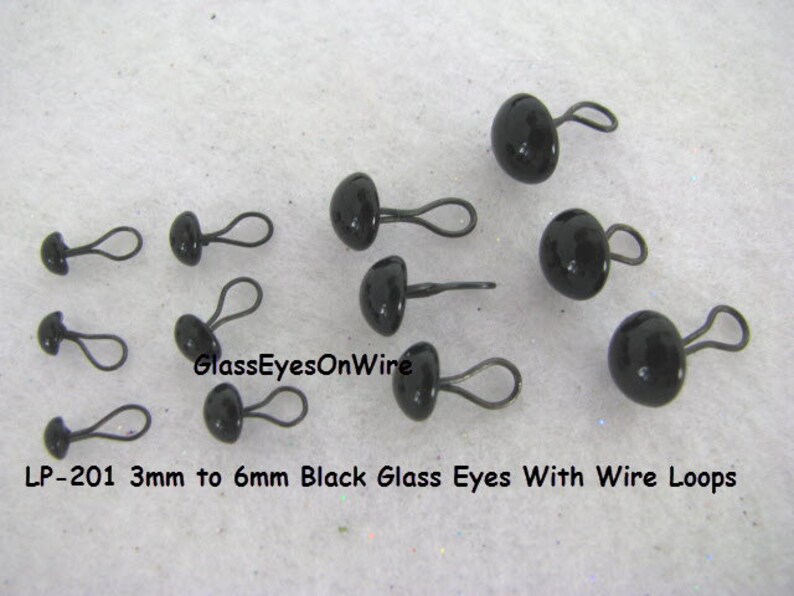May include: Assortment of black glass eyes with wire loops, ranging in size from 3mm to 6mm.  LP-201 3mm to 6mm Black Glass Eyes With Wire Loops