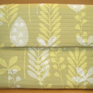 May include: A green laptop sleeve with a white and yellow floral pattern.
