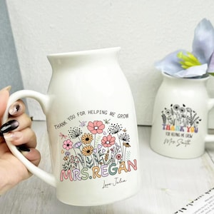 Può includere: Tazza in ceramica bianca con manico curvo, con un design floreale e la scritta "THANK YOU FOR HELPING ME GROW MRS.REGAN Love Julia". È visibile anche una tazza più piccola con un design simile.
