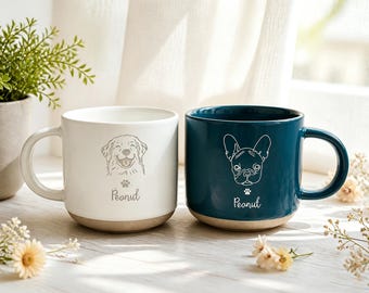 May include: Two ceramic mugs with a smooth finish and a natural base. The white mug features a line-art illustration of a golden retriever and the name Peanut. The dark teal mug features a line-art illustration of a French bulldog and the name Peanut.