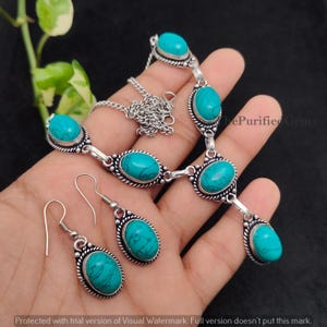 Può includere: Un set di gioielli color argento con collana e orecchini abbinati. Il set include pietre turchesi ovali incastonate in un'elaborata lavorazione del metallo. La collana ha una catena e gli orecchini sono a goccia.