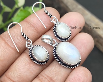 Puede incluir: Un conjunto de joyas con un colgante y pendientes a juego. El conjunto incluye un colgante plateado con una piedra ovalada de color blanco lechoso y dos pendientes con piedras similares. Los pendientes tienen un diseño de gancho. The Purified Gems.