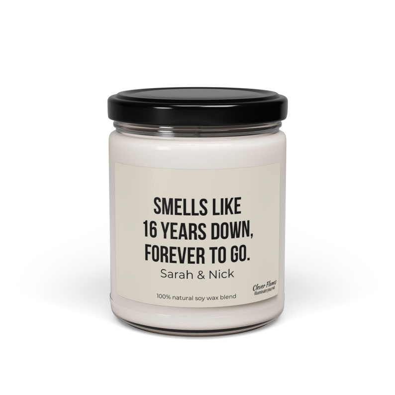 May include: A white candle jar with a black lid. The label reads "Smells like 16 years down, forever to go. Sarah & Nick 100% natural soy wax blend".