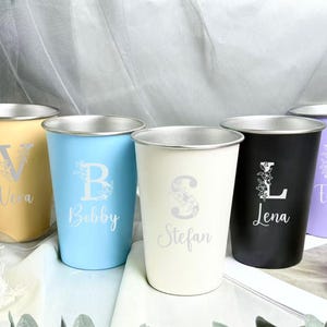 以下が含まれることがあります： パステルカラーのステンレス製タンブラー5個セット。イエロー、ブルー、クリーム、ブラック、ラベンダー。各タンブラーはシルバーの縁取りで、文字と名前がパーソナライズされています。文字は花の模様で装飾されています。