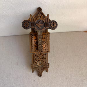 May include: A rectangular bronze-toned metal door plate featuring intricate relief carvings of a bird, floral patterns, and geometric lattice designs. The hardware includes a central circular opening and two circular side accents with spokes.