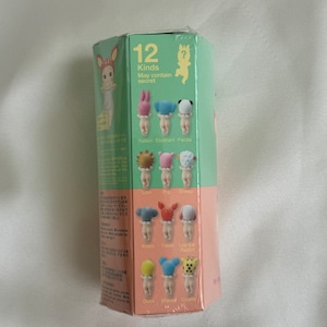 May include: A sealed, hexagonal box in green and pink. The box displays illustrations of small figurines with animal-themed hats. Text on the box reads "12 Kinds May contain secret" and lists animal names such as Rabbit, Elephant, and Panda.