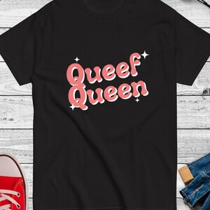 May include: Black t-shirt with a pink graphic that says "Queef Queen" with stars on either side.