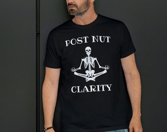 Puede incluir: Una camiseta negra con un gráfico blanco de un esqueleto sentado en una postura meditativa. El texto "POST NUT CLARITY" está impreso sobre el esqueleto.