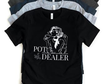Puede incluir: Camiseta negra con un gráfico blanco de una mujer tomando café y el texto "POT DEALER" con granos de café debajo.