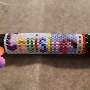 Puede incluir: Un bol&iacute;grafo negro con un dise&ntilde;o de cuentas blancas que dice "cruisin'" en colores arco&iacute;ris.