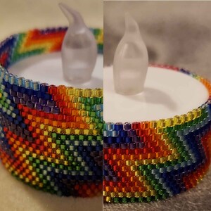 May include: A rainbow beaded candle holder with a clear plastic flame. The holder is made of small, colorful beads and is perfect for adding a touch of color to any room.