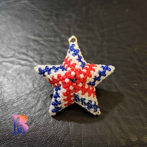 May include: A red, white, and blue beaded star ornament. The star is made of small beads and has a gold loop at the top for hanging.