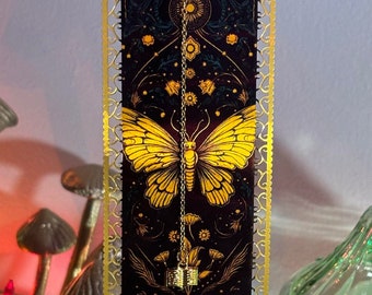 May include: A gold-framed decorative hanging with a black background featuring a yellow butterfly and floral designs. The hanging has a gold chain with a small gold charm.