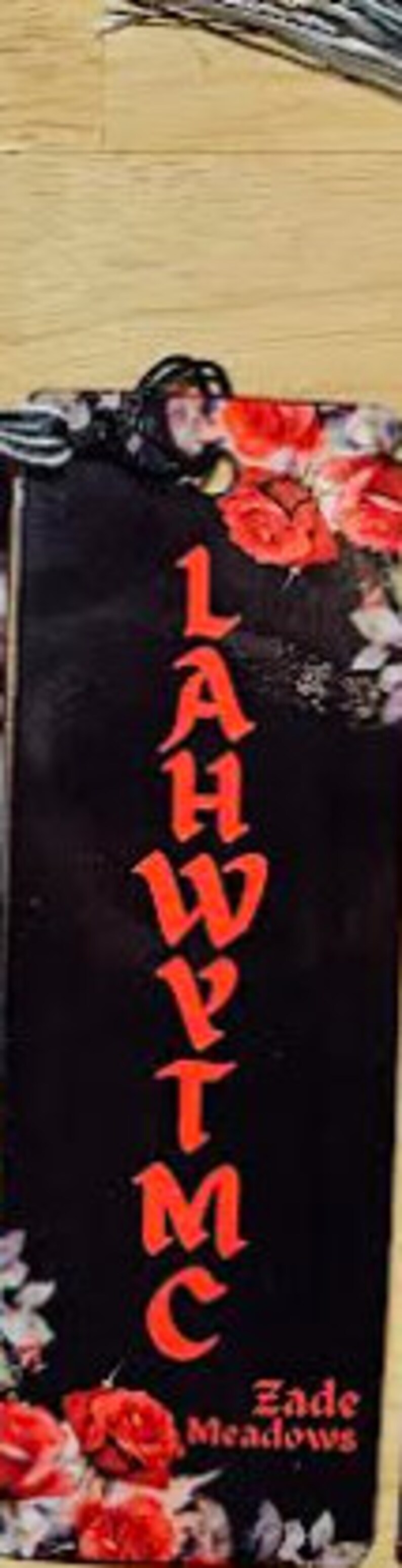 May include: Black bookmark with red floral design and the text "L.A.H.Y.T.M.C." and "Zade Meadows" at the bottom.