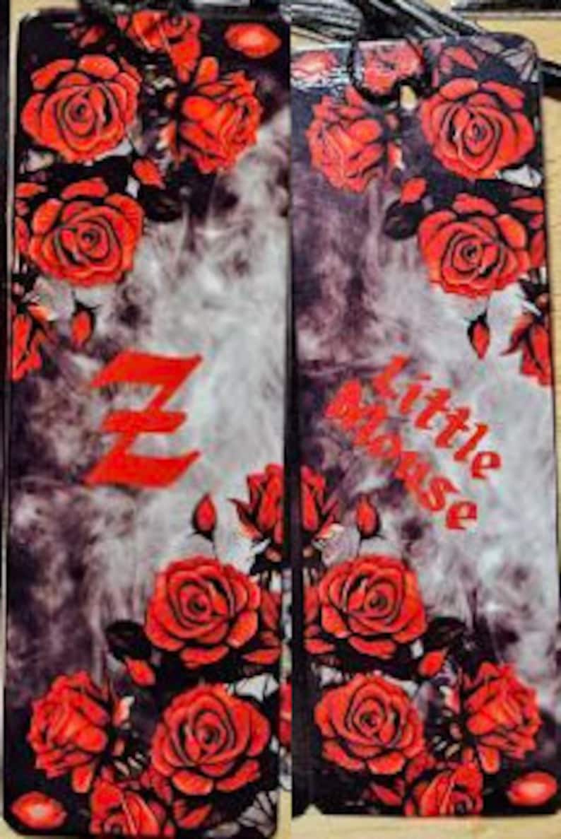 May include: Two black and gray bookmark with a red rose pattern. The left bookmark has a red letter Z and the right bookmark has the word "little blouse" in red.