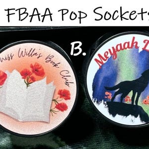 May include: Two round pop sockets. One features a book and red poppies with the text "Miss Willa's Book Club". The other has a wolf silhouette, flowers, and the text "Meyaah Liessa" against a watercolor background.